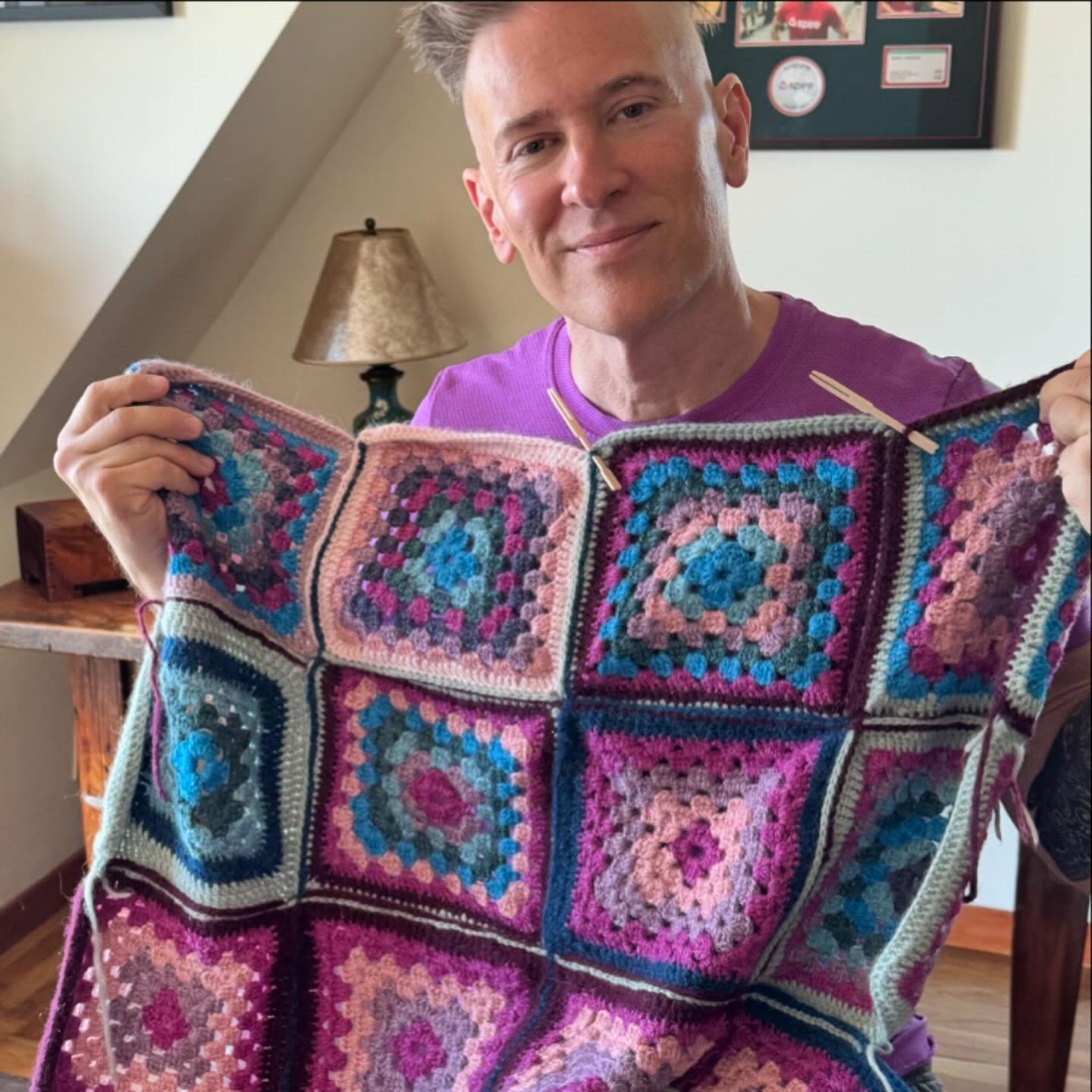 Andy holding a granny-square afghan he crocheted